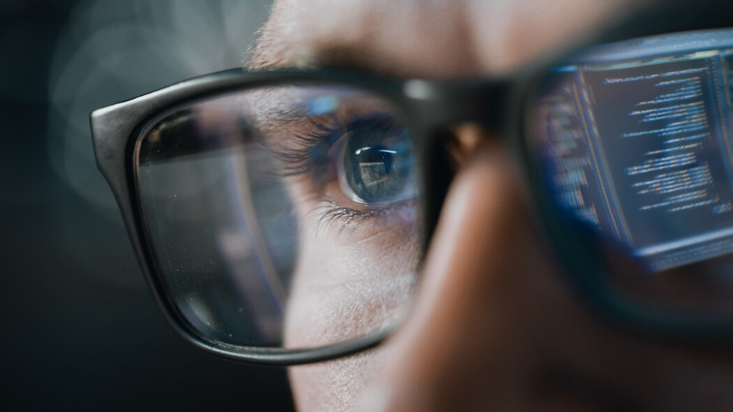 close-up-portrait-of-software-engineer-working-on-computer-line-of-code-reflecting-in-glasses-developer-working-on-innovative-e-commerce-application-using-machine-learning-ai-algorithm-big-data